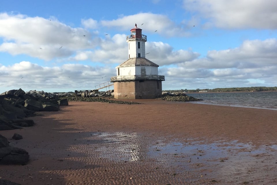 A lighthouse on a rocky shore with a clear sky.