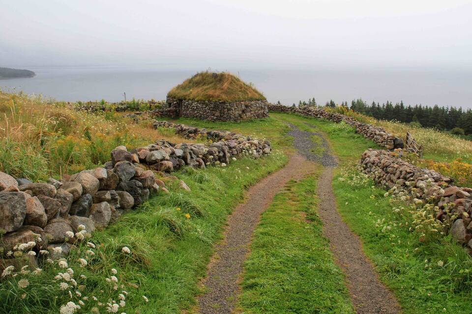 A stone wall, a grassy mound, and a path leading to the ocean.