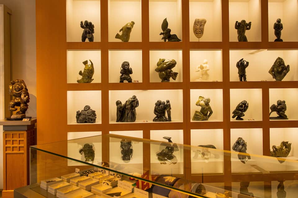 A museum display of various sculptures in glass cases.