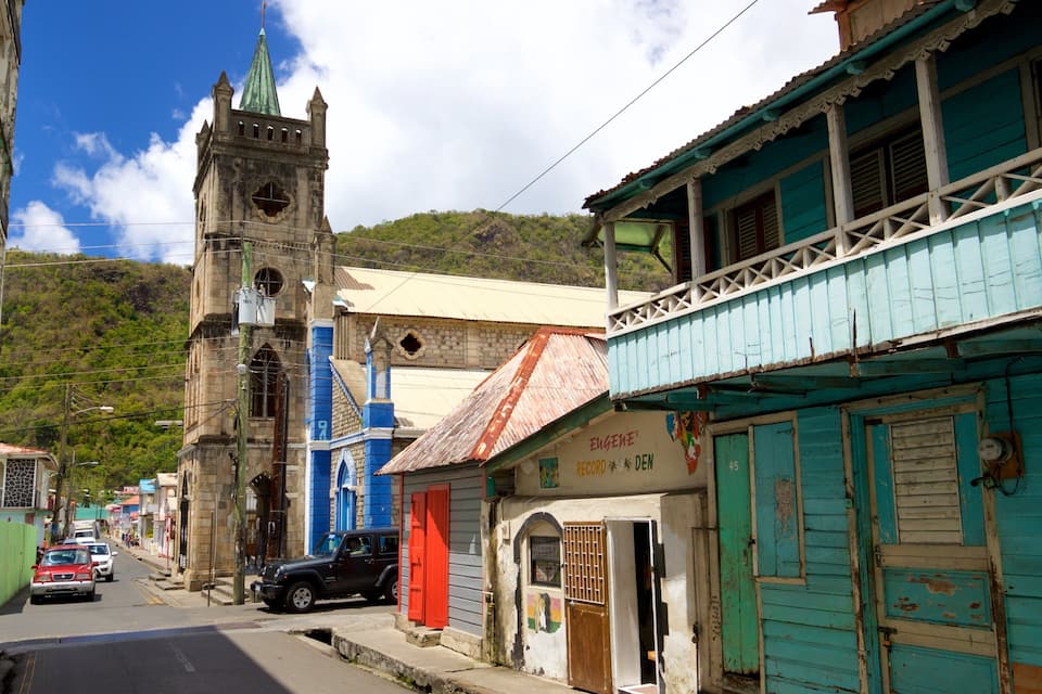 Une rue avec un clocher d’église, un immeuble bleu et un panneau indiquant « STOP ».