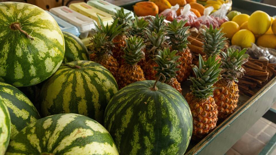 A display of watermelons and pineapples at a market.