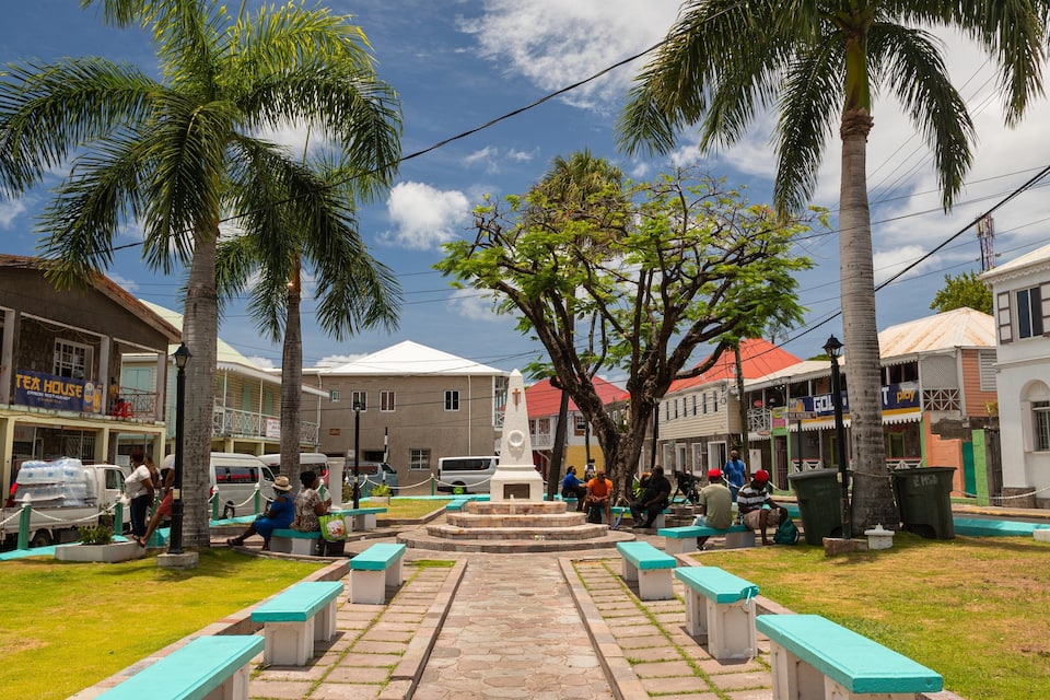 A public square with benches, palm trees, and buildings with signs like "Tea House" and "GOLTV."