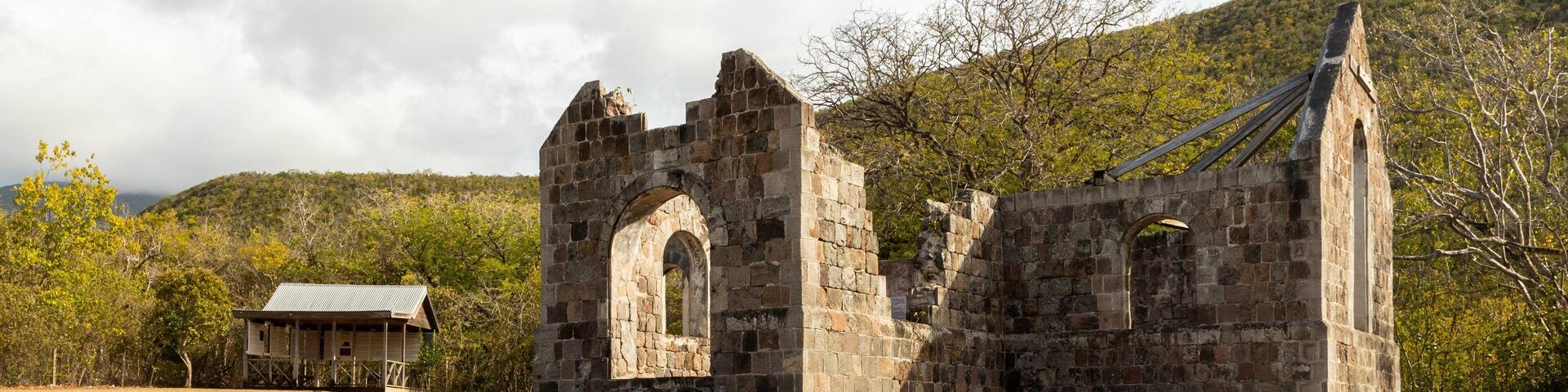 Un edificio antiguo de piedra con ventanas de arco y una pequeña construcción de madera cerca.