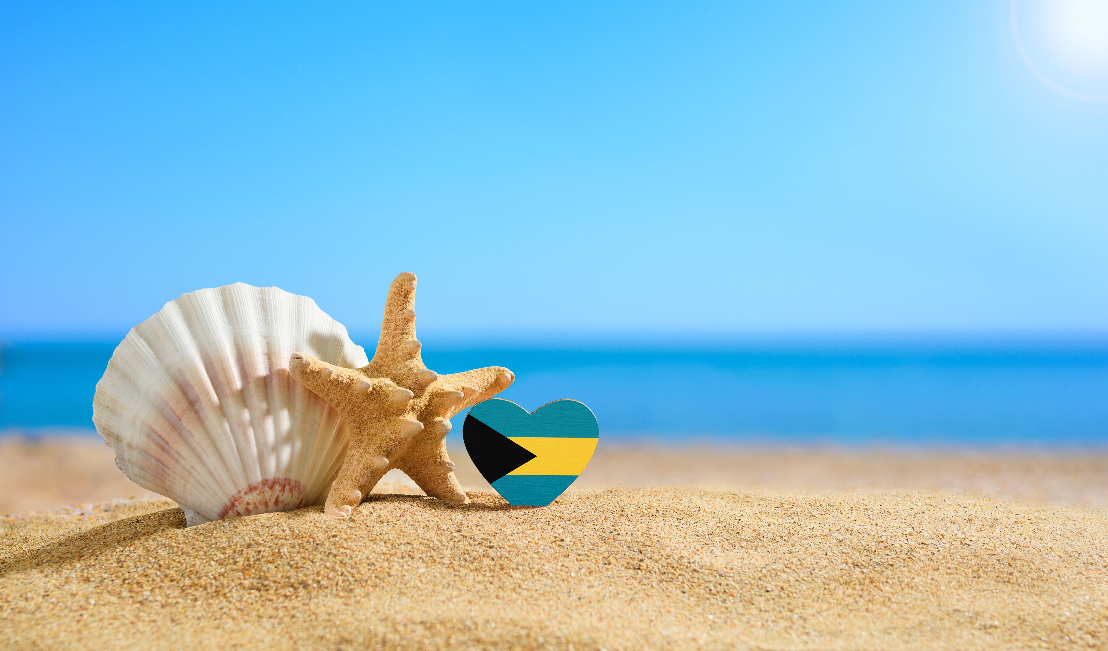 Beautiful beach in the Bahamas. Flag of Bahamas in the shape of a heart and shells on a sandy beach.