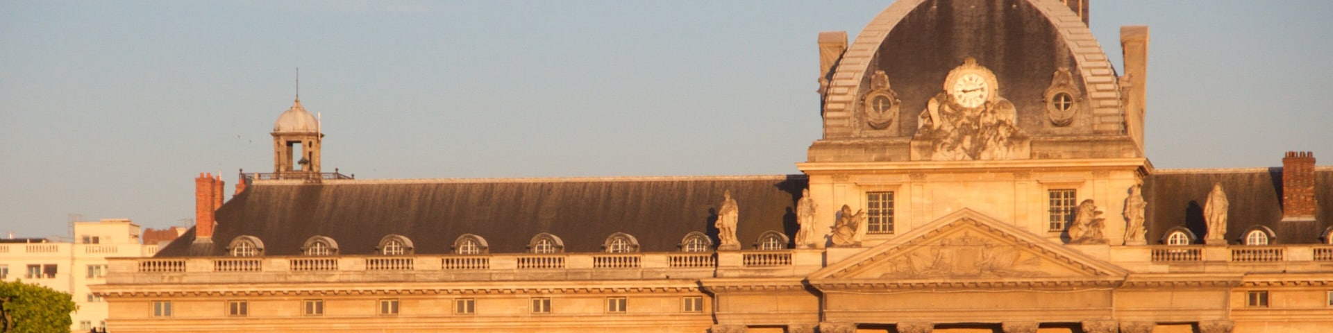 Un edificio histórico grande con una imponente torre del reloj y una estatua en el techo.