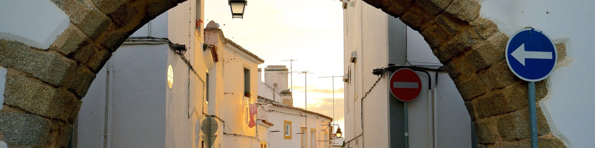 Uma rua de paralelepípedos sob um arco de pedra, com edifícios de ambos os lados.