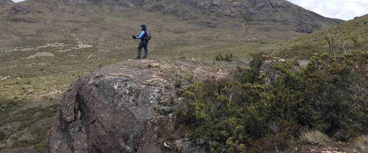 A hiker on a rocky outcrop overlooking a mountainous landscape.