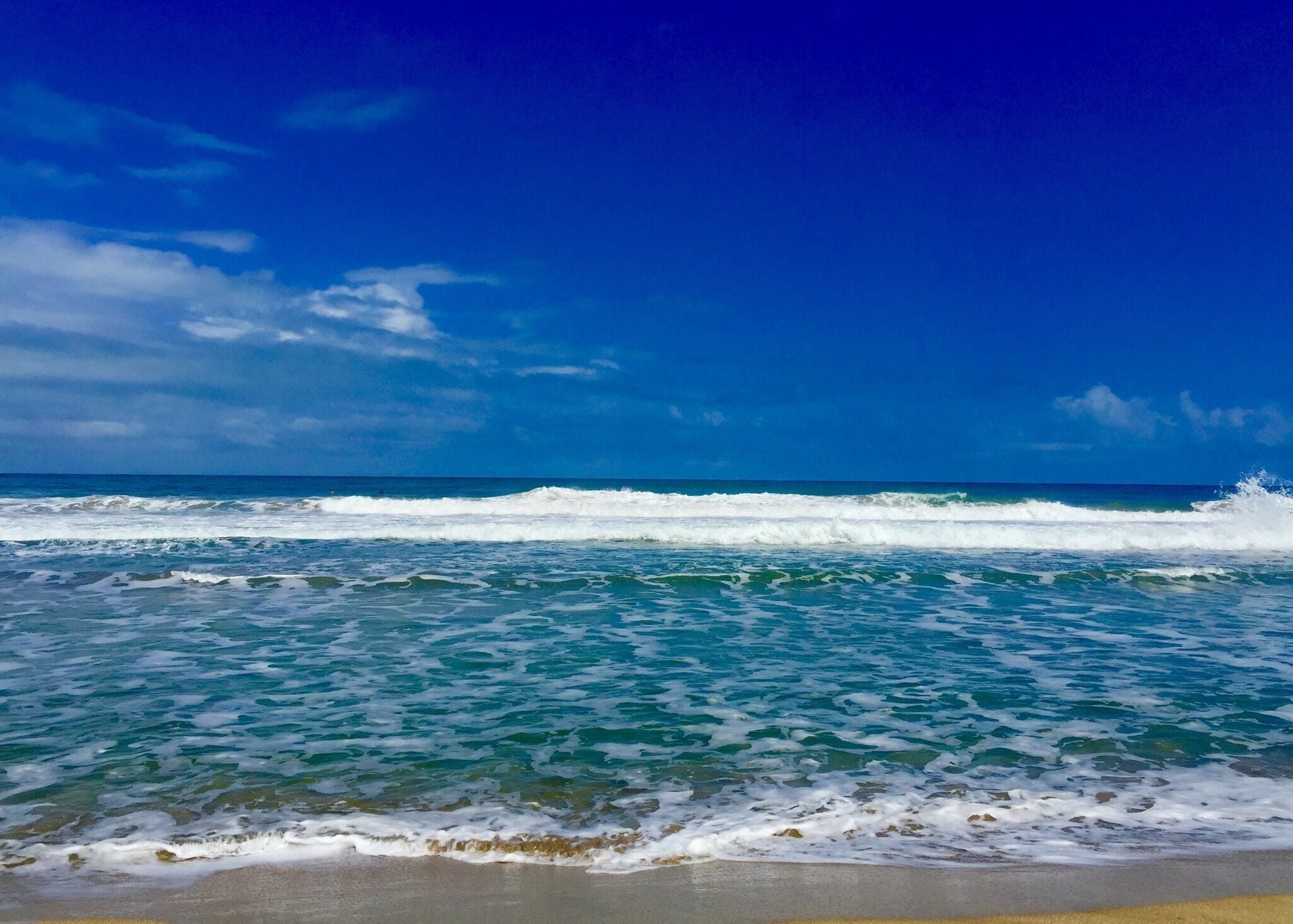 Uma praia com águas azul-claras e ondas.