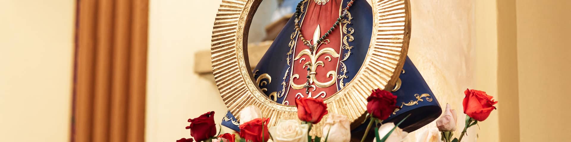A religious statue with a golden frame, surrounded by a bouquet of roses.