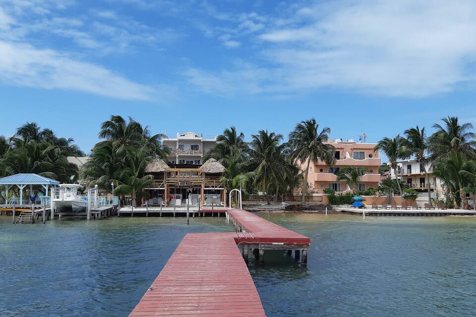 A waterfront resort with a red pier, palm trees, and beach houses.