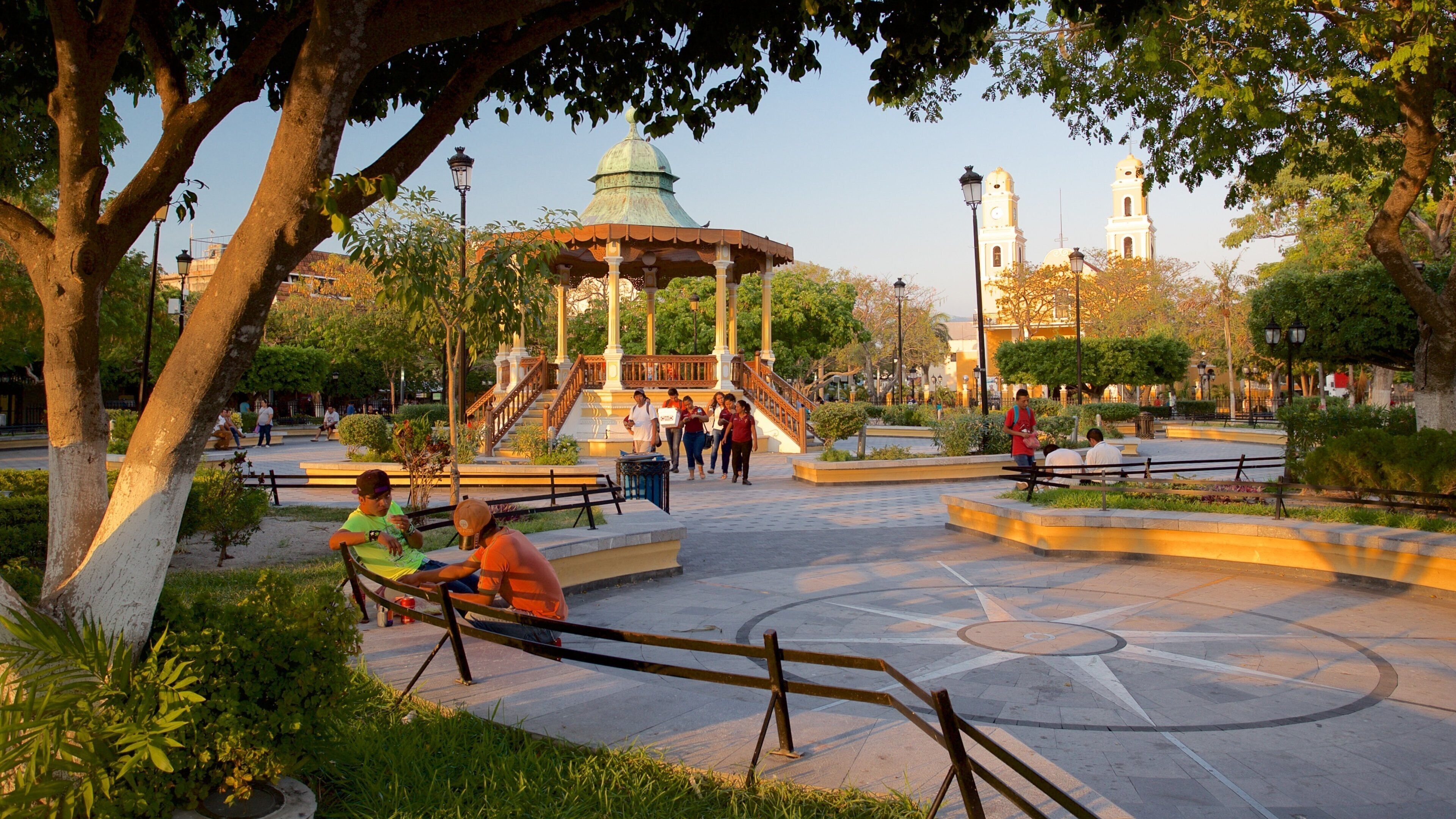 Zaragoza Park showing a garden and a sunset as well as a small group of people