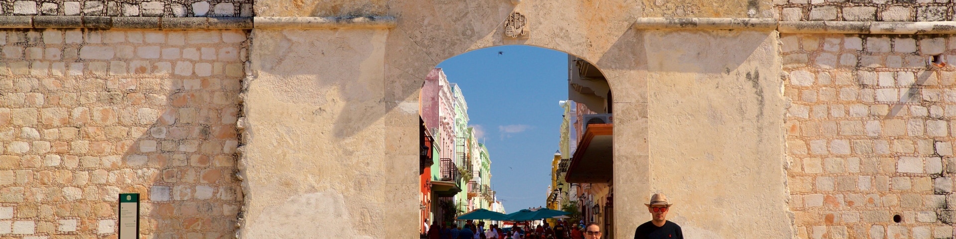 Un antiguo arco de piedra por donde caminan personas.