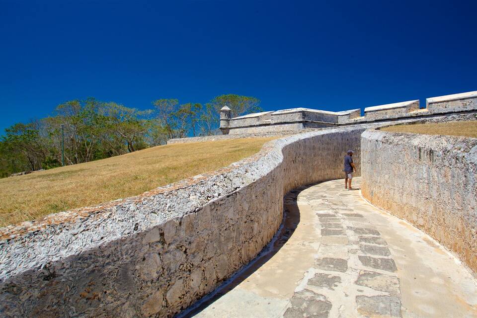 A stone pathway leading up a curved wall with a person walking.