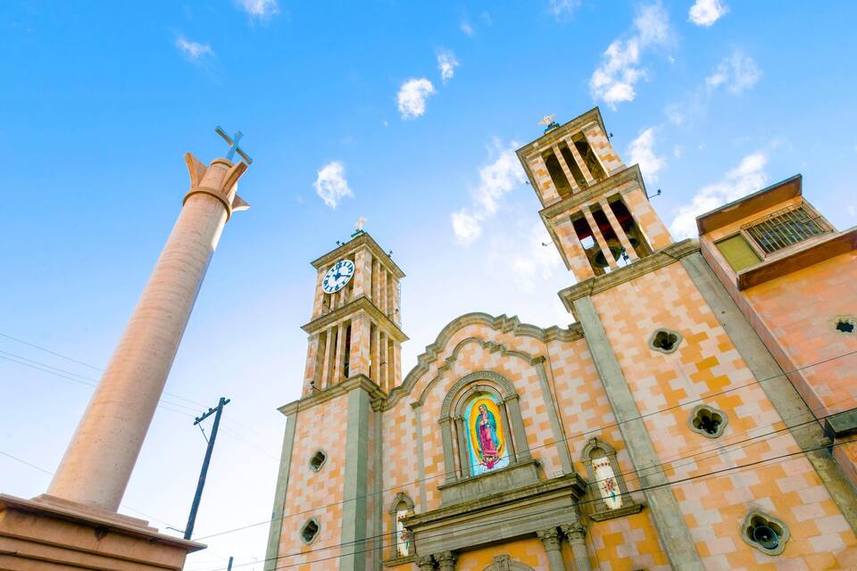 Una iglesia con un alto campanario, un reloj y un vitral.