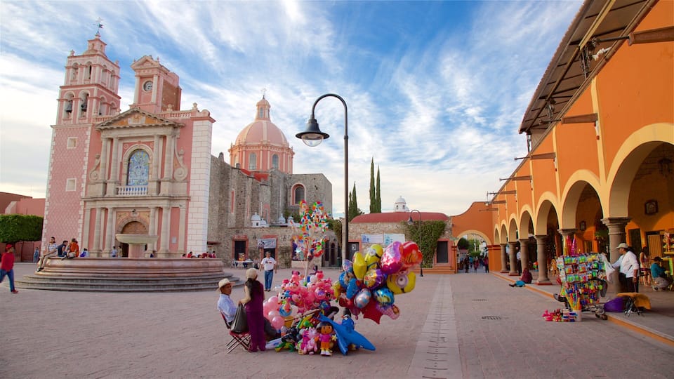 A plaza with a pink church, a fountain, and colorful balloons.