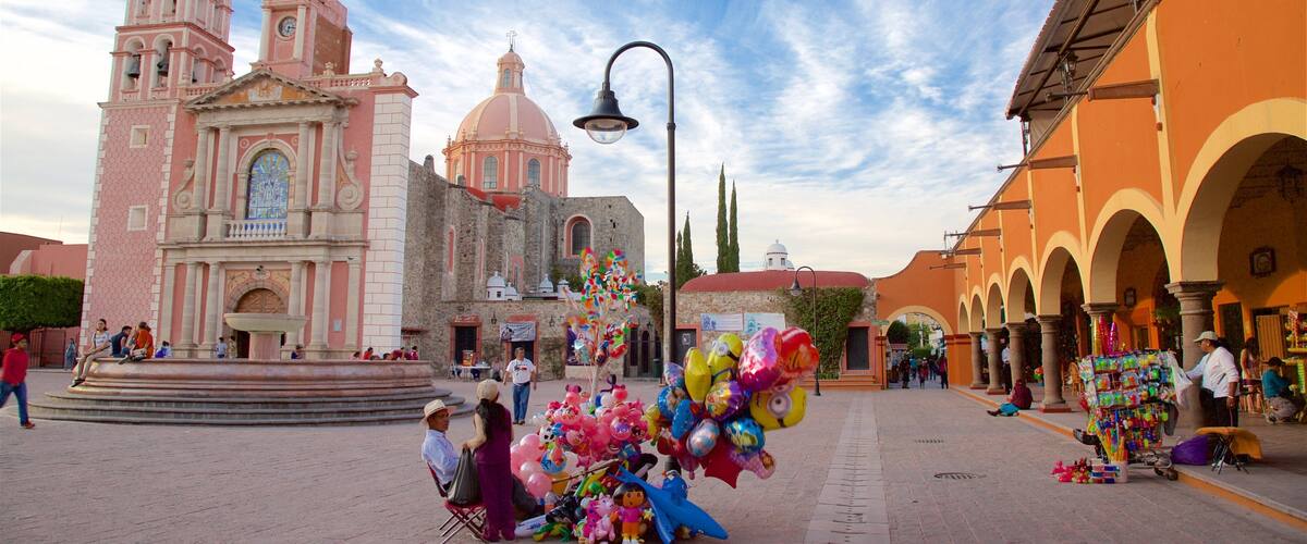 A plaza with a pink church, a fountain, and colorful balloons.