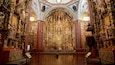 Ein prunkvolles Kircheninnere mit aufwendigen Goldzierarbeiten, einem zentralen Altar und religiösen Gemälden.