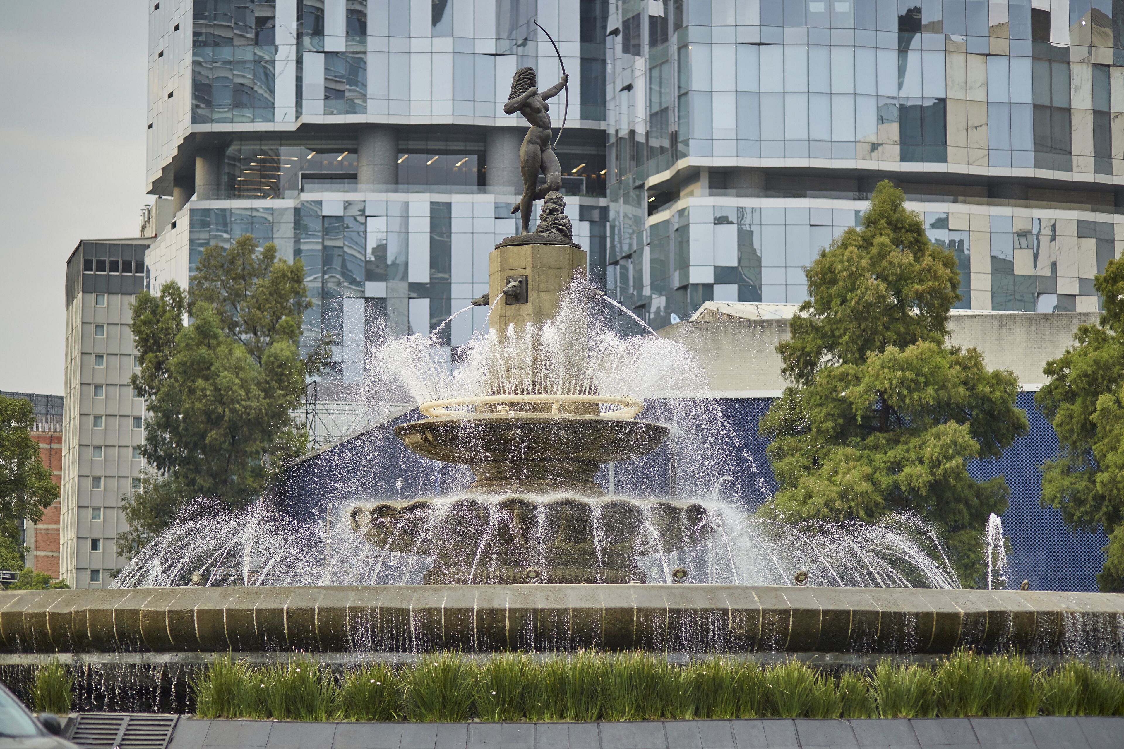 Huntress Diana Fountain against a modern glass building in Mexico City
