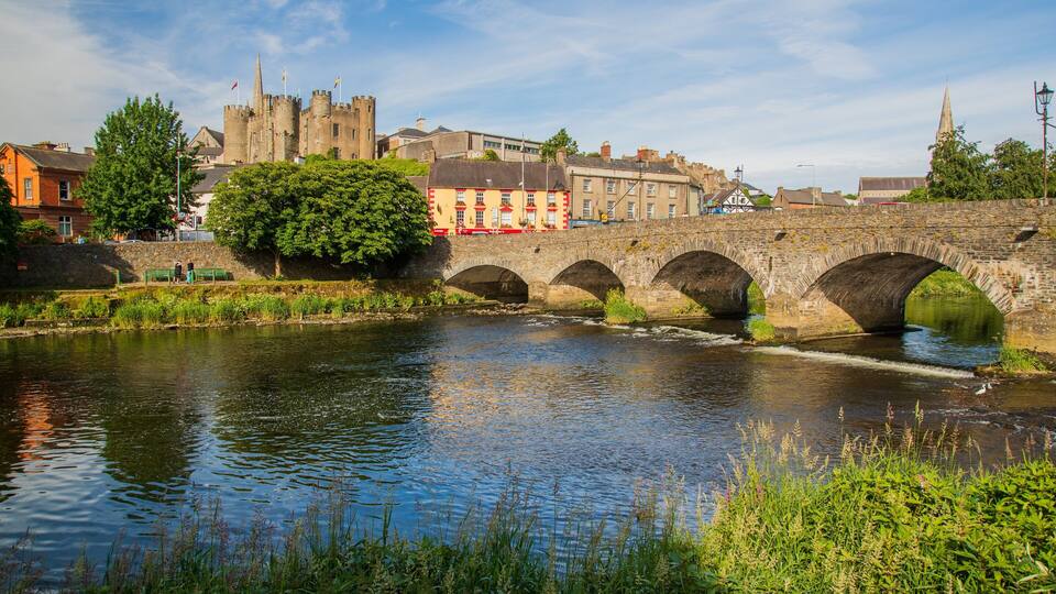 A stone bridge over a river with a castle in the background.