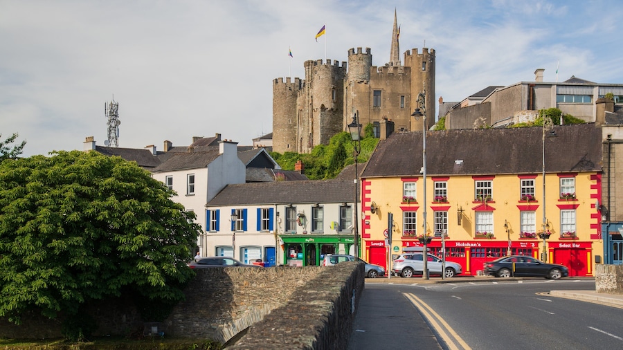 A street with colorful buildings, a castle in the background, and a stone wall.