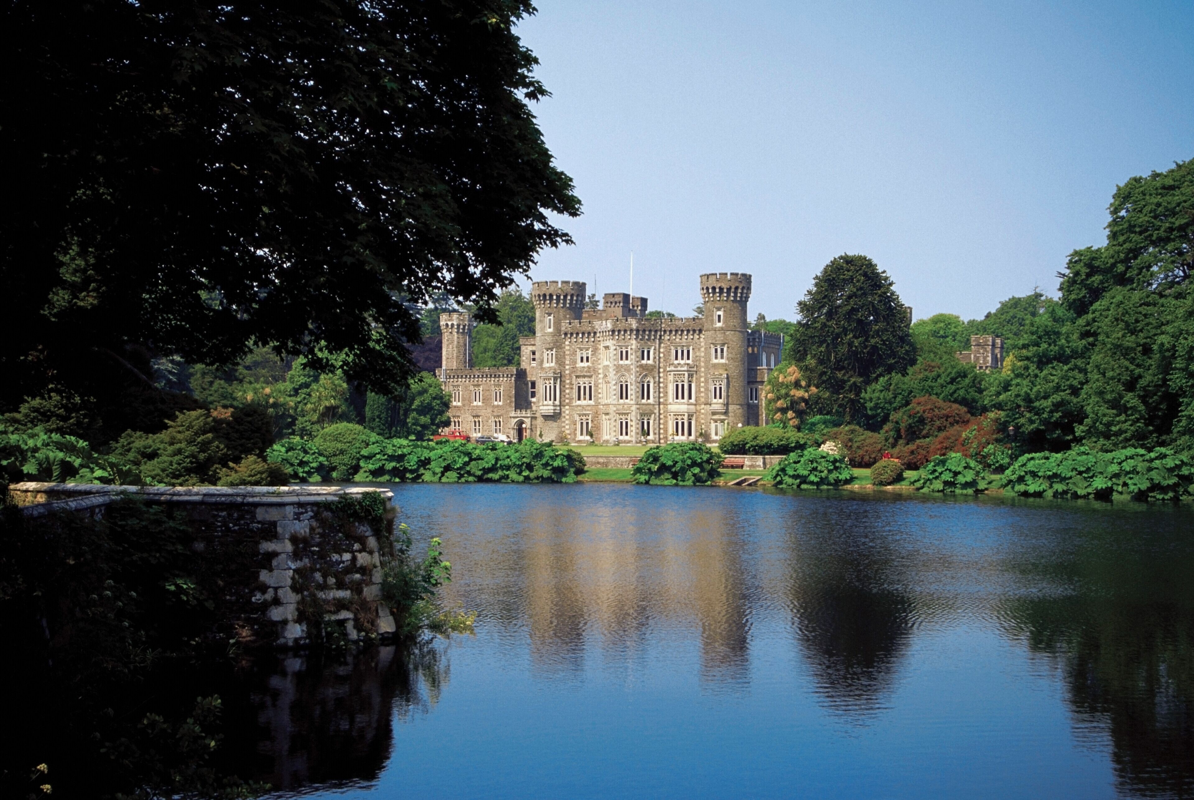 A castle surrounded by a lake and lush greenery.