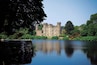 A castle surrounded by a lake and lush greenery.