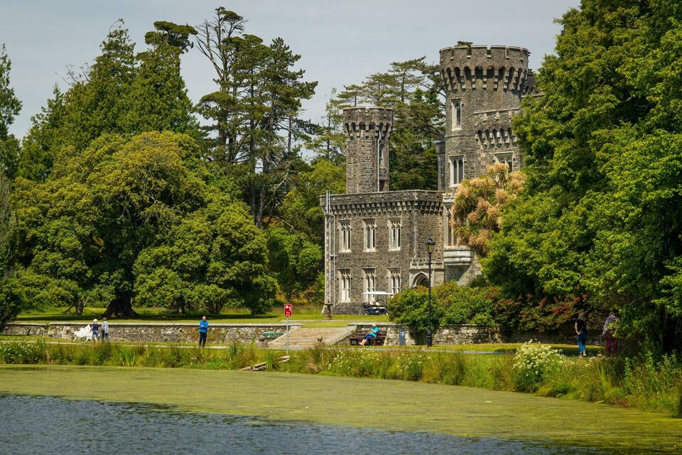A historic castle surrounded by lush greenery and a calm lake.