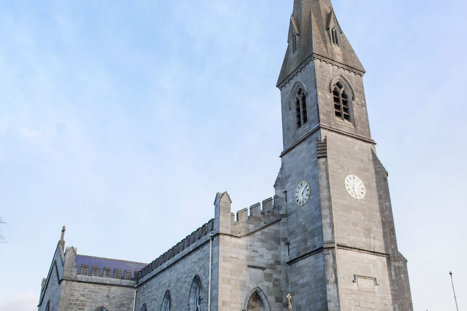 A large stone church with a tall tower and a clock.