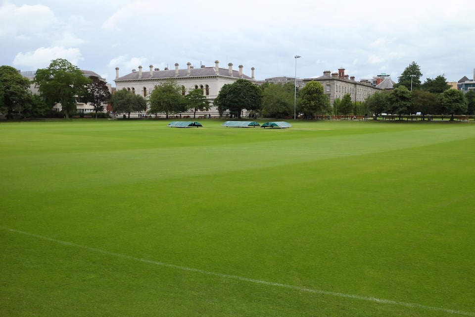 A large green field with a historic building in the background.