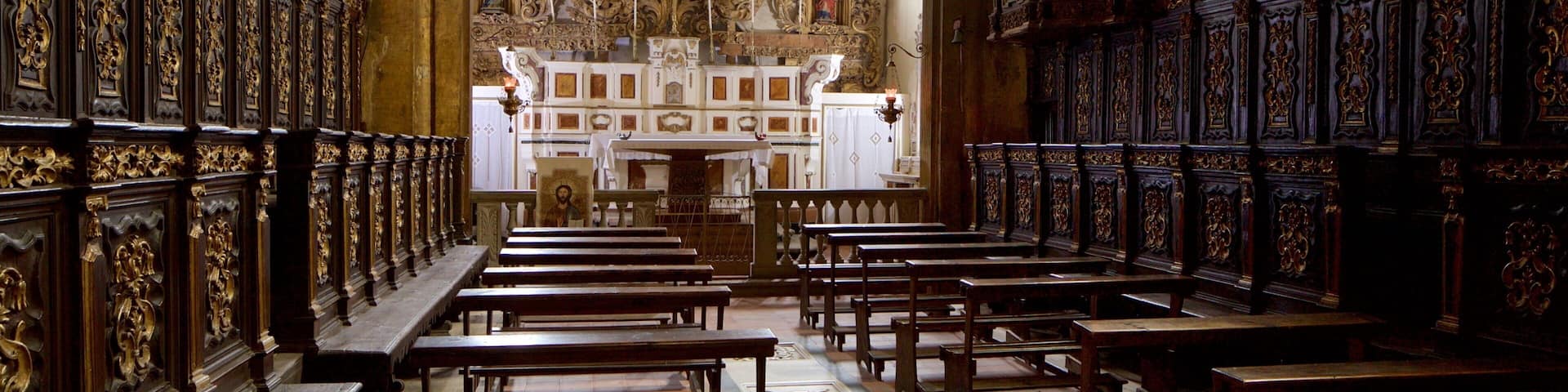 Interior ornamentado de una iglesia, con hileras de bancas, un altar central y elaboradas decoraciones en las paredes.