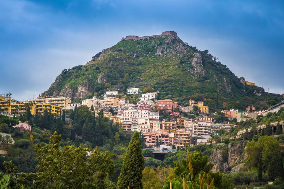 Un pueblo construido en una ladera con un castillo imponente en la cima.