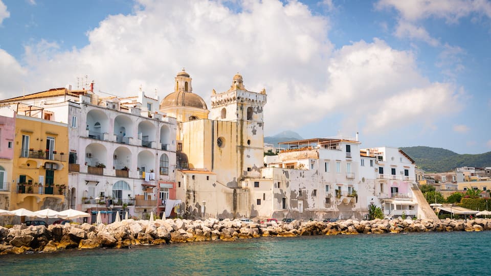 A coastal town with historic buildings, a prominent tower, and a rocky shoreline.
