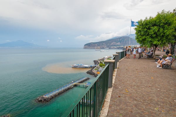Une promenade en bord de mer offrant une vue dégagée sur la mer, avec un quai et des bateaux.