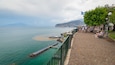 A waterfront promenade with a clear view of the sea, a jetty, and boats.