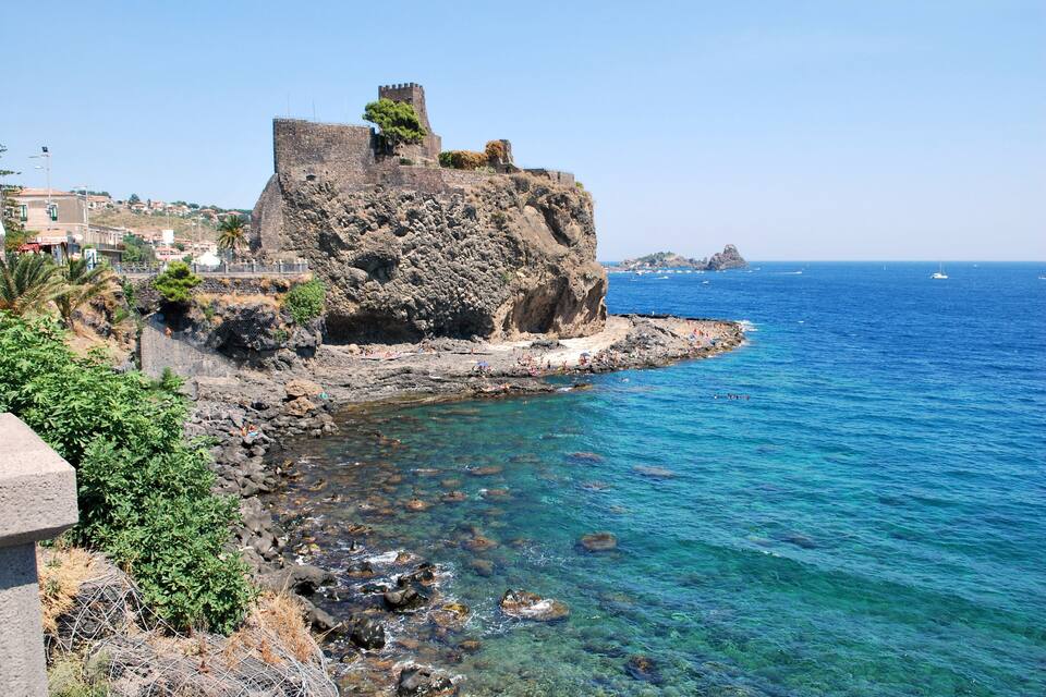 A coastal town with a prominent rocky cliff and a castle on top.