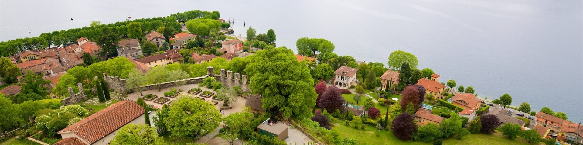 A riverside town with historic buildings, vineyards, and a large body of water.