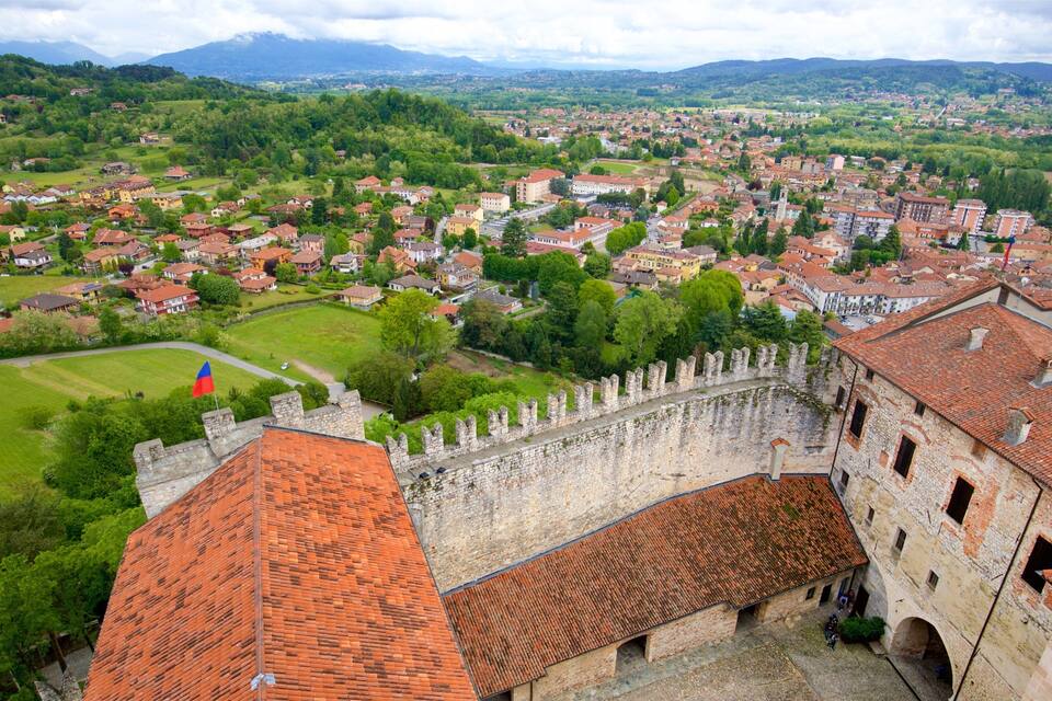 A historic town with a prominent castle, lush green hills, and a river in the background.