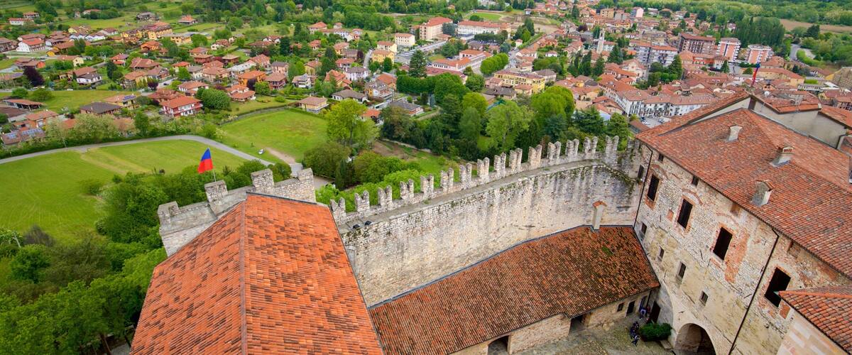 A historic town with a prominent castle, lush green hills, and a river in the background.