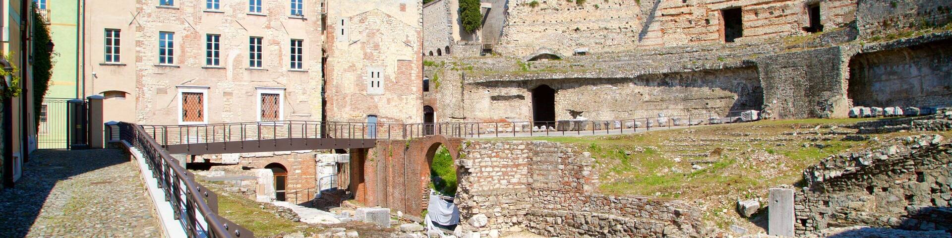 An ancient amphitheater with ruins and a modern building in the background.