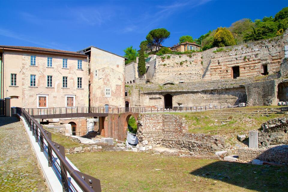 An ancient amphitheater with ruins and a modern building in the background.