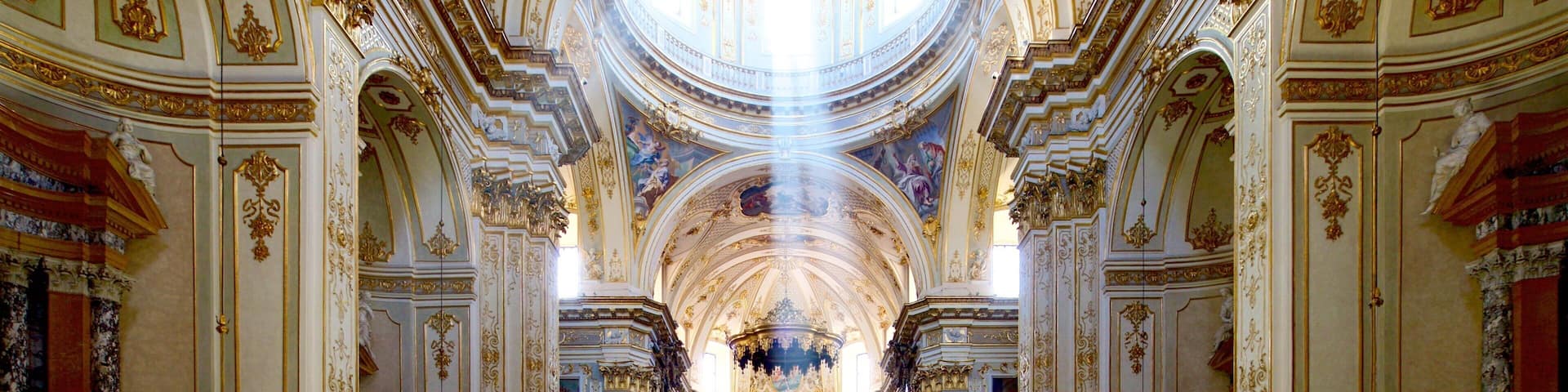 Interior ornamentado de una iglesia con techo alto, candelabros y detalladas decoraciones en las paredes.