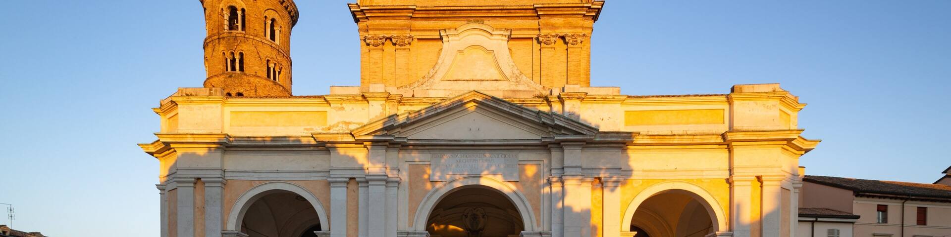 Una iglesia histórica con un campanario y una cúpula, que presenta arquitectura clásica y un cielo despejado.