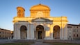 A historic church with a bell tower and a dome, featuring classical architecture and a clear sky.