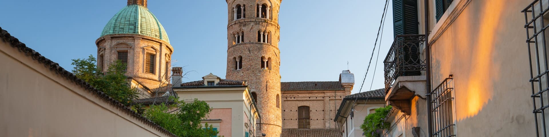 A narrow street with a church tower and a dome.