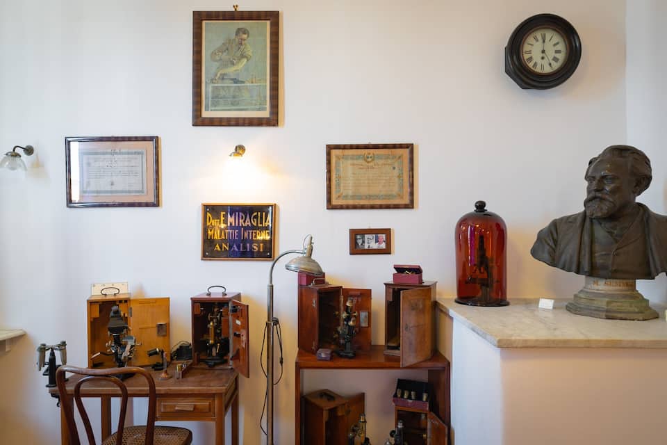 Une pièce contenant divers instruments scientifiques, un buste et des documents encadrés accrochés au mur.