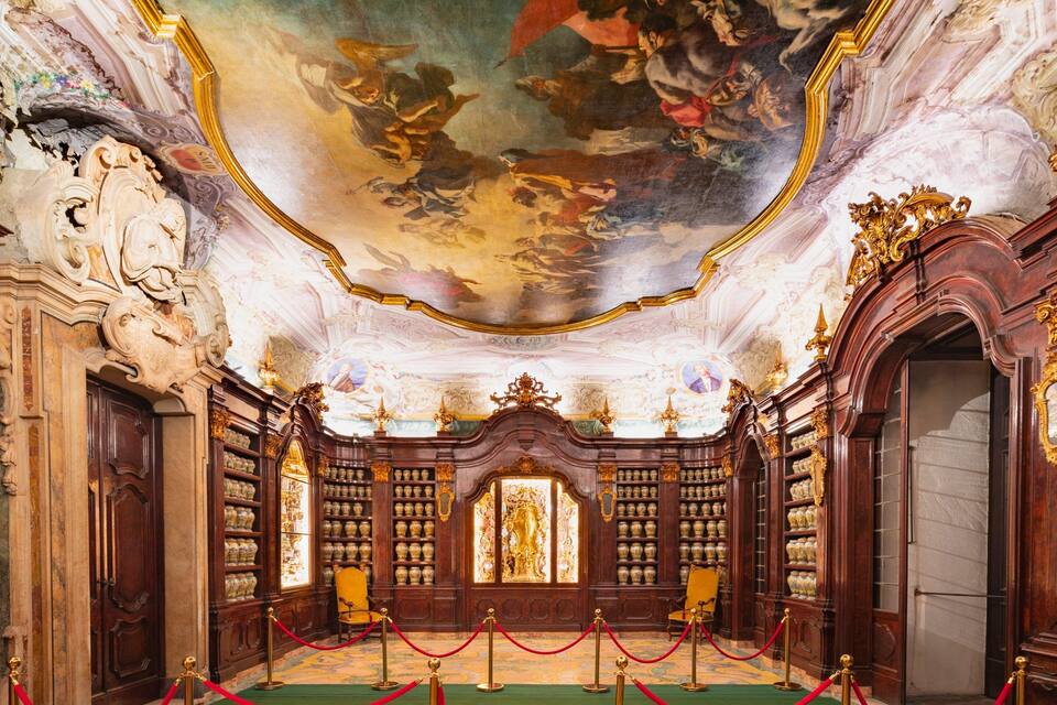 An ornate room with a high ceiling, elaborate woodwork, and a collection of vases on shelves.