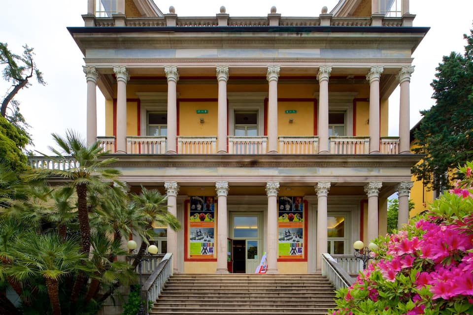 Un edificio storico con un balcone, colonne e una scalinata che conduce all'ingresso.