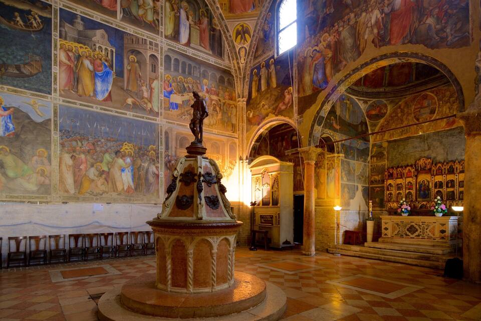 A church interior with frescoes, a central statue, and a large altar.