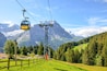 Yellow cable car in the Swiss Alps. Gondola going from Grindelwald to First in the Jungfrau area. Summer Alpine landscape with snowcapped mountains in the background. Transport tourists uphill