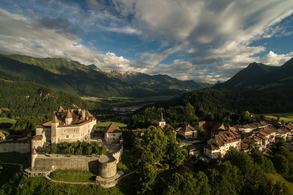 Un château historique, entouré de collines verdoyantes et d’une vallée.